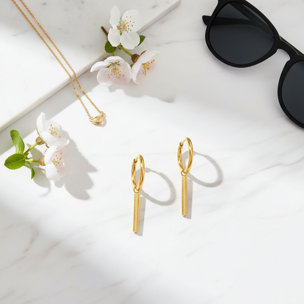 Minimalist flat lay of gold bar earrings on marble with accessories